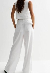 White cropped top and wide-leg pants in lightweight fabric. The outfit features a clean design, smooth texture, and a minimalist style.