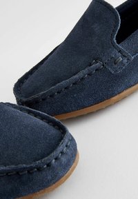 Mocassini in camoscio blu navy con dettagli di cucitura e punta arrotondata. La suola in gomma offre aderenza. La texture morbida e il design semplice aumentano il comfort.