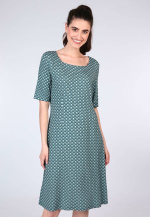 Kurzärmliges, türkisfarbenes Kleid mit quadratischem Ausschnitt und diamantförmigem Muster. Ausgestellte Silhouette, die knieumspielend fällt. Weicher Stoff.