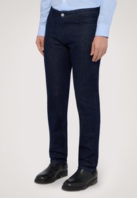 Mörkblå denimjeans med slim fit, med en standard femfickdesign och en enda metallknappslås i midjan.