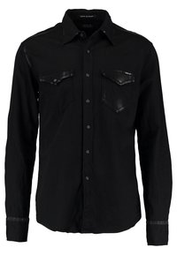 Camicia nera a maniche lunghe in cotone con due tasche sul petto, chiusura con bottoni e dettagli in pelle sulle spalle e sulle tasche.
