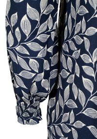 Tissu bleu marine avec motif de branche feuillue blanche et poignet élastique froncé sur la manche longue.