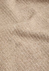 Beige gebreide stof met een gestructureerd patroon van fijne verticale ribbels, met een zachte, iets grove afwerking en subtiele variaties in tint.