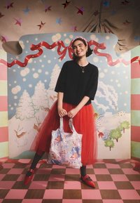 Színes vászontáska játékos mintával. A képen piros tüllszoknya, fekete pulóver és piros cipő csatos részletekkel.