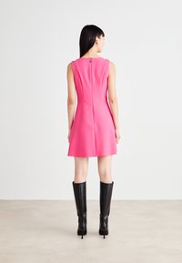 Fitted sleeveless dress in bright pink with a flared skirt, featuring a back zipper and a subtle design at the neckline.