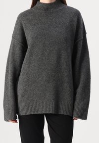 Pull gris foncé oversize avec un col montant côtelé, des épaules tombantes et un bord-côte à l'ourlet ; confectionné dans un tissu doux et texturé.