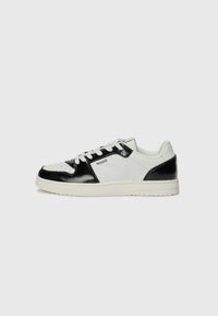 Sneakers sintetiche bianche e nere con accenti lucidi, punta forata, lacci rotondi e suola in gomma testurizzata. Logo sul lato.