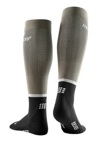 Knöchelhohe Fußballsocken in olivgrün und schwarz, strukturierter Stoff, weiße Akzente, verstärkte Fersen und Zehen, mit gemustertem Grip auf den Sohlen.