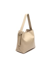 Beige nahkakäesammsi, jossa on säädettävä hihna ja leveä, avara yläosa. Silkinomainen pinta, minimalistinen muotoilu ja terävä pohja.