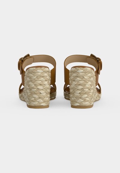 Sandales en cuir marron avec brides à la cheville et hauts talons compensés tissés espadrille, vues de dos sur fond blanc.