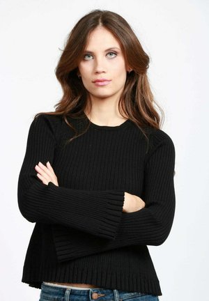 Maglione nero in maglia a costine con scollatura rotonda, maniche lunghe e polsini svasati. L'orlo è leggermente accorciato con una finitura testurizzata.