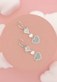 Silverörhängen med två hjärtformer, där ett har en randig textur. Designen inkluderar ett litet kopplande hjärta och en spärrbackslåsning.