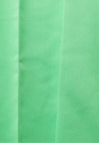 Green textured fabric with a smooth finish, featuring subtle diagonal patterns and faint creases. Lightweight and flexible material.