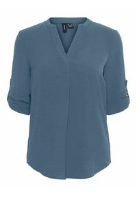 Blouse bleue avec un col en V, manches trois-quarts retroussées, tissu lisse et ourlet légèrement arrondi. Design simple et polyvalent.