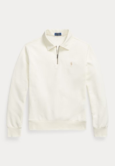 Polo à manches longues de couleur crème avec fermeture éclair d'un quart, col, poignets et ourlet côtelés, et petit logo brodé sur la poitrine gauche.