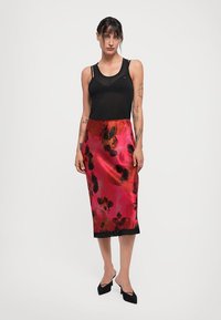 Fustă midi din satin în roz vibrant, cu modele florale negre, având un tiv din dantelă neagră transparentă. Asortată cu un top din bumbac negru ajustat.