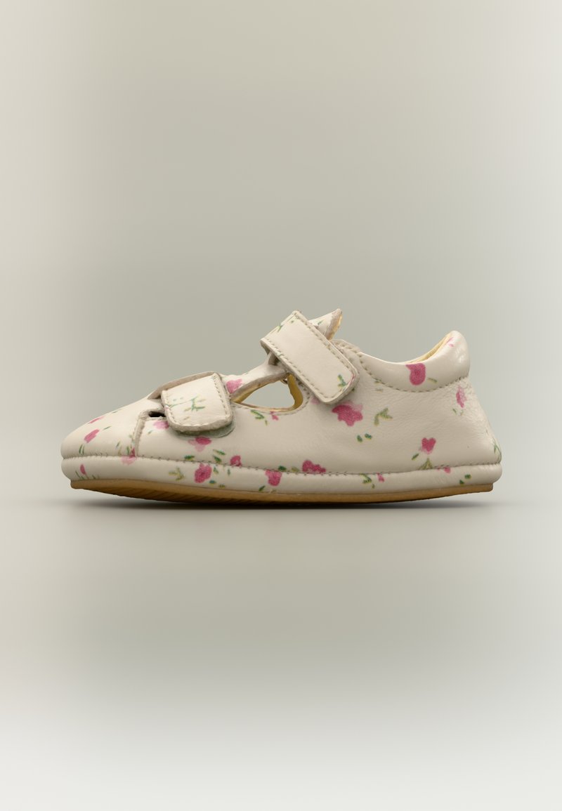 Κρεμ δερμάτινο παπούτσι με ροζ και πράσινο λουλουδάτο μοτίβο, αυτοκόλλητα λουράκια και στρογγυλεμένη μύτη. Λεπτή καουτσούκ σόλα για ευελιξία.