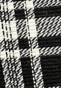 Schwarz-weiß kariertes Gewebe mit einer strukturierten Webart. Enthält abwechselnde Muster aus Quadraten und diagonalen Linien. Weiches, gestricktes Material.