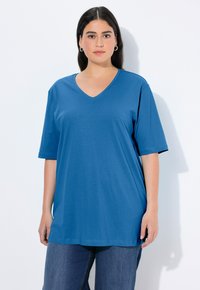 Blue v-neck t-shirt with short sleeves, made of soft fabric, relaxed fit, and a smooth texture. Paired with loose blue denim pants.