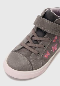 Szare zamszowe sneakersy z wzmocnionym czubkiem, różową gumową podeszwą i haftem motyli w różowym i purpurowym po boku. Zapięcie na rzepy i sznurówki.