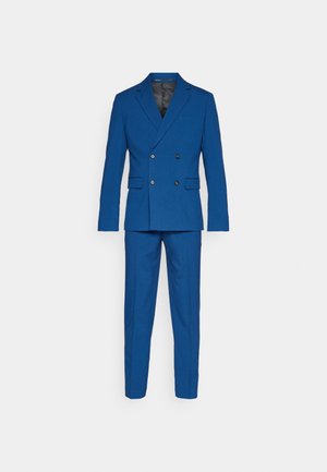 Traje azul de doble botonadura con solapa de muesca, dos bolsillos frontales y pantalones a medida a juego, con una textura de tela suave.