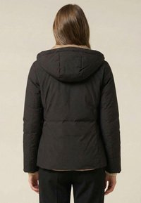 Czarna pikowana kurtka z kapturem, o gładkiej fakturze i dopasowanym kroju. Szczegóły obejmują kontrastującą beżową podszewkę wewnętrzną.