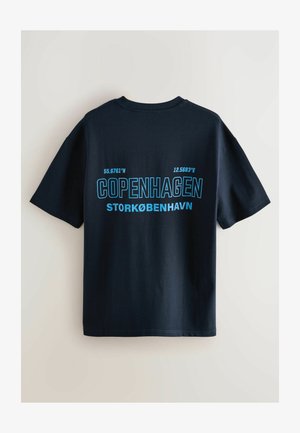 Námořnické bavlněné tričko s výrazným modrým textem "KODAŇ" a souřadnicemi, krátkými rukávy a kulatým výstřihem.