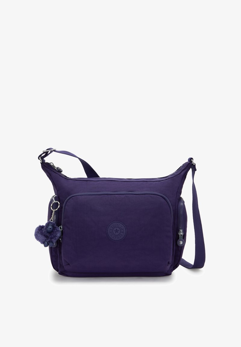 Lila Stoff-Schultertasche mit einem Reißverschluss-Hauptfach, einer Fronttasche und einem angeklebten pelzigen Charme. Mit einem verstellbaren Tragen.