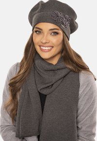 Berretto a maglia grigio con accento floreale e sciarpa coordinata. Tessuto morbido, vestibilità rilassata, design texture; entrambi gli articoli si completano a vicenda.