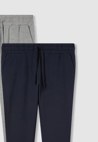 Due paia di pantaloni della tuta: uno grigio e uno blu navy. Entrambi presentano una vita elasticizzata, un laccio e tasche laterali. Materiale in cotone morbido.