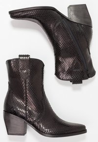 Bottes noires jusqu'à la cheville avec un motif texturé en cuir de reptile, dotées d'une fermeture éclair sur le côté, d'une languette de traction et d'un talon empilé.