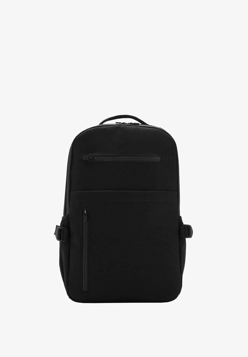 Sac à dos noir avec une texture lisse, doté d'une fermeture éclair sur le dessus, d'une poche zippée à l'avant et de sangles avec boucle sur le côté pour un ajustement personnalisable.