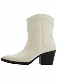 Białe botki kowbojskie z sztucznej skóry do kostki z zaostrzonym noskiem, pionowymi przeszyciami oraz dekoracyjnymi wykrojami. Czarne, blokowe obcasy.