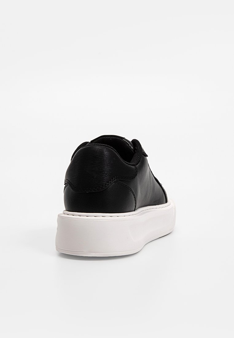 Czarne skórzane sneakersy o eleganckim designie, z teksturowaną cholewką, białą gumową podeszwą i minimalistycznymi detalami w szwach.