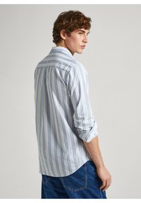 Chemise à manches longues, boutonnée, en rayures bleu clair et blanches ; tissu doux avec une coupe décontractée ; ourlet arrondi ; manches retroussées.