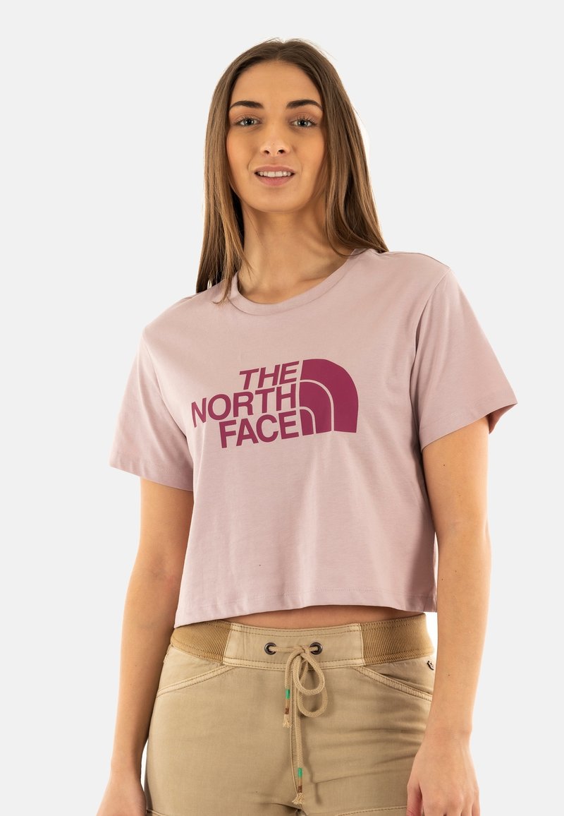 T-shirt corta rosa chiaro con il logo "THE NORTH FACE" in rosa scuro. Maniche corte e scollatura rotonda.