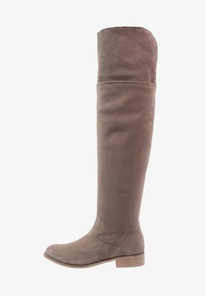 Botte haute en daim taupe avec un petit talon en bois et un bout arrondi, montant au-dessus du genou pour une couverture complète de la jambe.