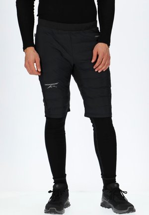 Black padded shorts with a stretchy waistband, paired with fitted black leggings. Features a small logo on the leg and textured fabric.