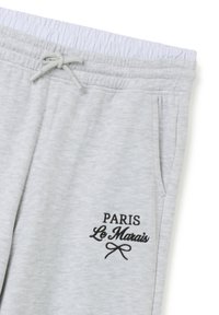 Hellgraue Jogginghose mit einem elastischen Bund und Kordelzug, Taschen und schwarzem gesticktem Text "PARIS Le Marais."