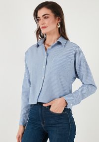 Blue and white striped button-up shirt with a collared neck, chest pocket, and long sleeves. Made from lightweight fabric.