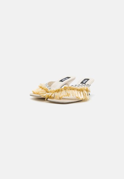 Open-toe sandals in light beige with yellow fringe detailing along the front, black zigzag accents, and flat soles.