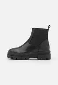 Botas Chelsea negras con acabado de cuero suave, paneles laterales elásticos, tirador y suela de goma gruesa con profundos relieves.