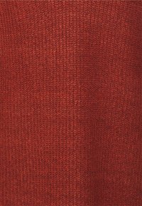 Tissu en tricot rouge avec une surface texturée, présentant un motif dense et côtelé. Le matériau semble doux et chaud, adapté aux vêtements.