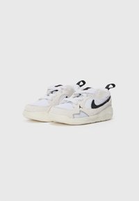 Ténis desportivos brancos com um upper em malha texturizada e camurça, apresentando um logo swoosh preto e solas brancas resistentes. Inclui um design de atacadores.