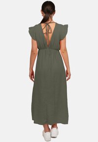 Robe longue sans manches, vert olive, avec des épaules froncées et un dos en V. Fabriquée en tissu texturé, elle tombe jusqu'aux chevilles.