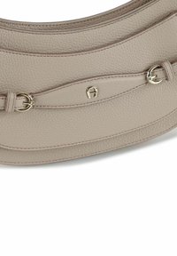 Borsa a mano in pelle beige dalla forma curva, con cuciture discrete, una texture liscia e dettagli in metallo color oro.