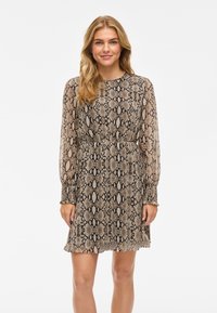 Långärmad klänning i beige och brun ormskinnsmönster, tillverkad av lättviktsmaterial med draperad midja och elastiska ärmslut.