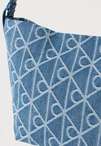Τσάντα χειρός από τζιν με γεωμετρικό μοτίβο σε ανοιχτό μπλε χρώμα. Το ύφασμα έχει υφή, με λείο λουράκι και ασημένιες μεταλλικές λεπτομέρειες.