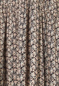 Tissu noir avec un petit motif floral dense en pêche douce et bleu clair, présentant des plis froncés formant des plis verticaux.