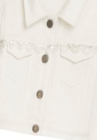 Weiße, verkürzte Jeansjacke mit metallischen Knöpfen, zwei Vordertaschen und einem silbernen Spitzenbesatz aus Pailletten über der Brust.